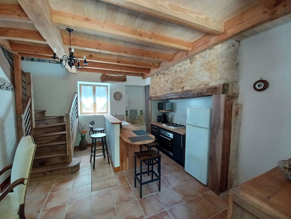 Une cuisine avec des poutres en bois, un mur en pierre, un four à micro-ondes et un réfrigérateur.