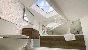 A modern bathroom with a skylight, a large mirror, and a white sink. - Charming 2-bed Apt With 2 Bathtub Central London (London)