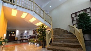 A spacious lobby with a marble floor, a staircase with wooden railings, and potted plants. - Yuedu Holiday Hotel (Yichun)