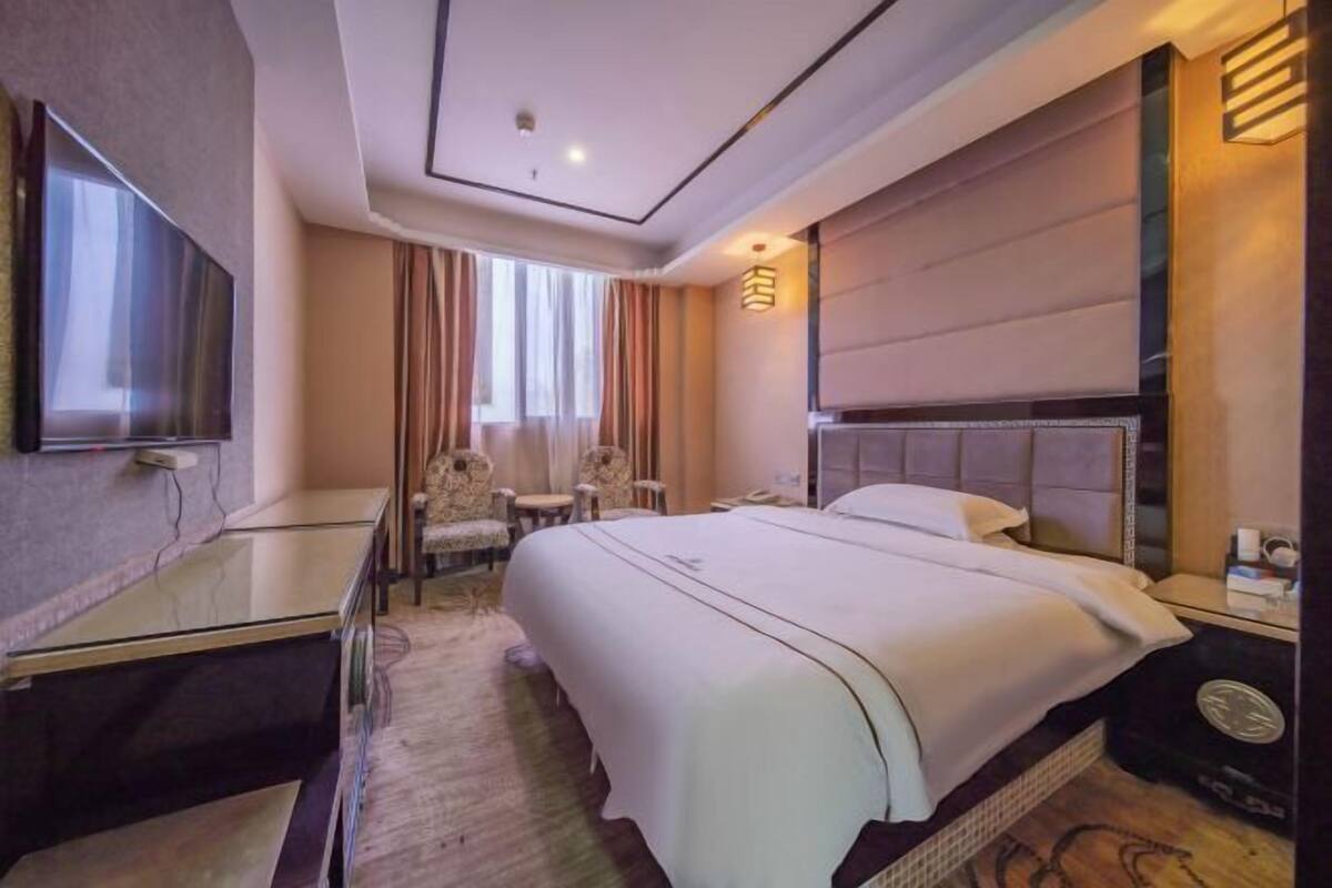 A hotel room with a large bed, a flat-screen TV, a desk, and a chair.