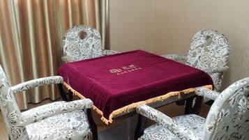 A dining table with a red tablecloth, four patterned chairs, and a curtain in the background.