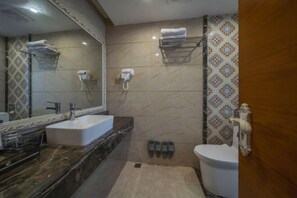 A bathroom with a large mirror, a sink, a toilet, and a shower area.