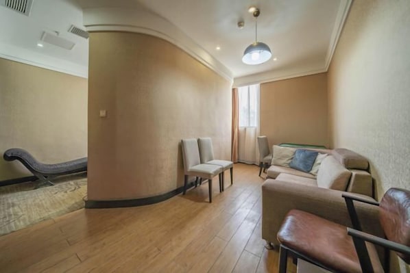 A spacious living area with a sofa, chairs, and a wooden floor.