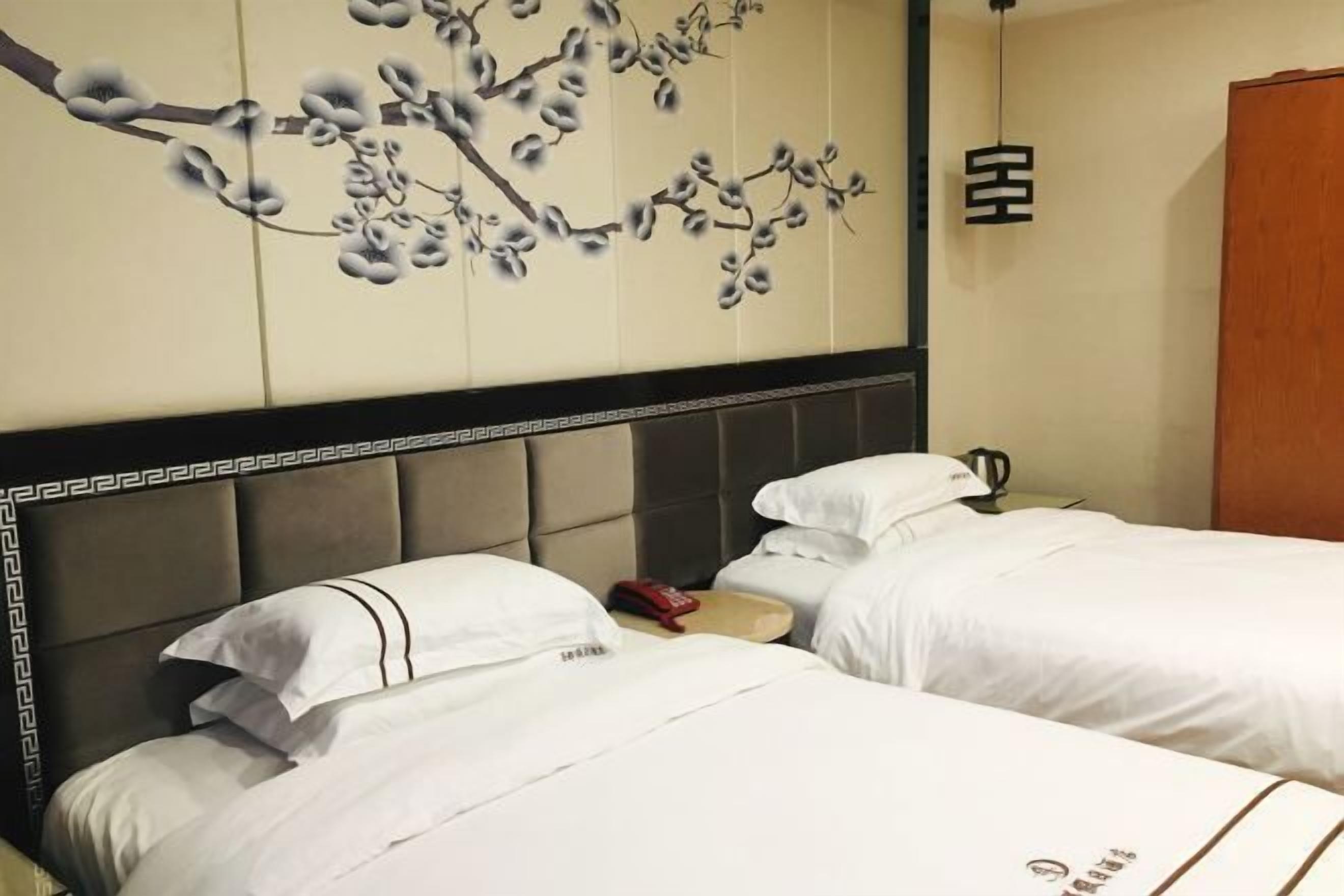 Hotellihuone, jossa on kaksi sänkyä, seinämaalaus, vaatekaappi ja yöpöytä.