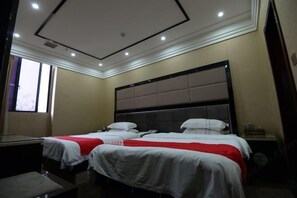 Una camera d'albergo con due letti, una scrivania e un'ampia finestra.