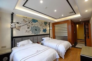 Habitación de hotel con dos camas, un mural decorativo y una lámpara en el techo.
