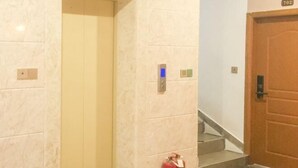 A hotel corridor with a marble wall, a wooden door, and a fire extinguisher. - Danzhou xillelai theme travel rental (Danzhou)