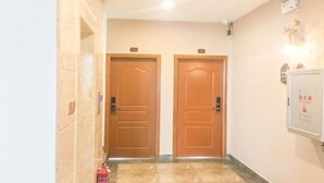A hallway with two wooden doors, a fire extinguisher, and a wall-mounted sign. - Danzhou xillelai theme travel rental (Danzhou)