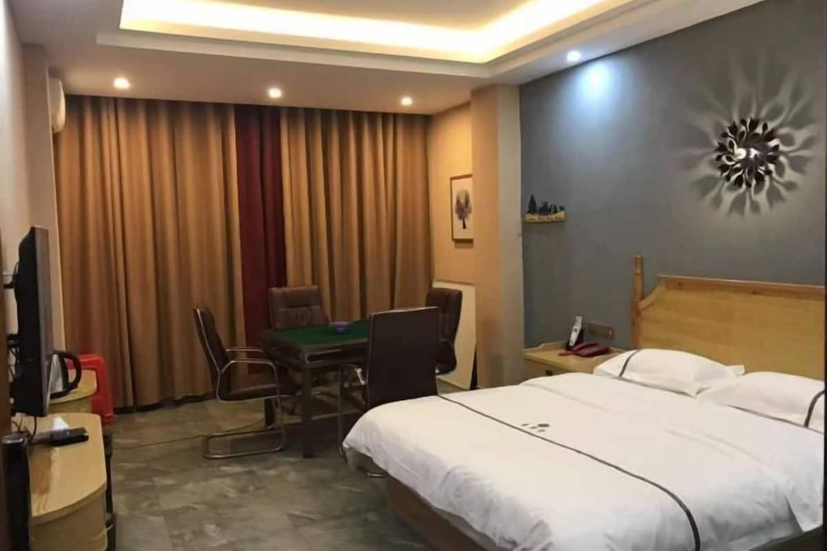 A hotel room with a bed, a desk with a chair, a television, and curtains.