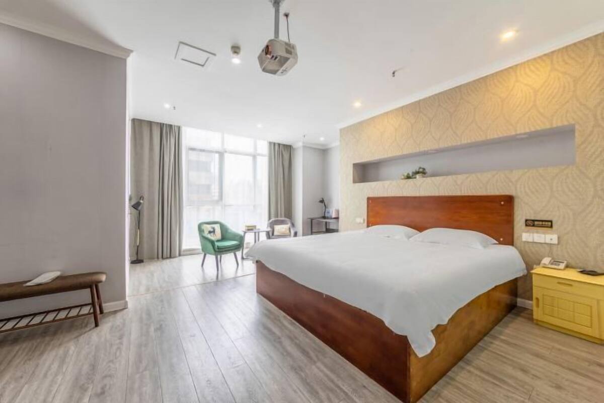 Ein Hotelzimmer mit einem großen Bett, einem Schreibtisch, einem Stuhl und einer Bank.