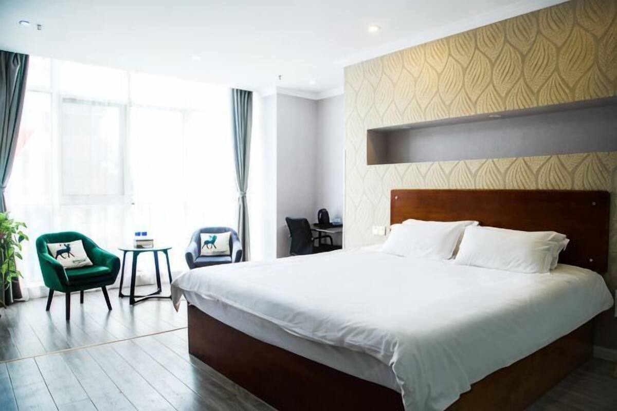 Ein Hotelzimmer mit einem großen Bett, einem Schreibtisch, einem Stuhl und einem kleinen Tisch.