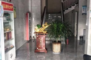 A lobby with a staircase, a reception desk, and a potted plant. - Lianyungang Xingjia Business Hotel (Suxin Kuai Station Branch) (Lianyungang)