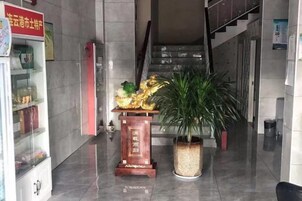 A lobby with a staircase, a reception desk, and a potted plant.
