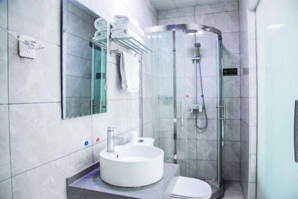 A modern bathroom with a round sink, a toilet, and a glass-enclosed shower.