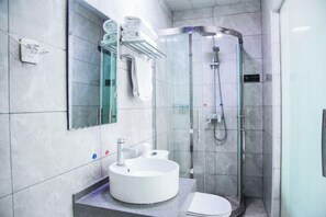 Une salle de bain moderne avec un lavabo rond, des toilettes et une douche à parois de verre.