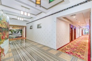 A hotel corridor with patterned flooring, a red carpet, and a wall with a mural. - Shengli Spa Holiday Hotel (Jiangmen)