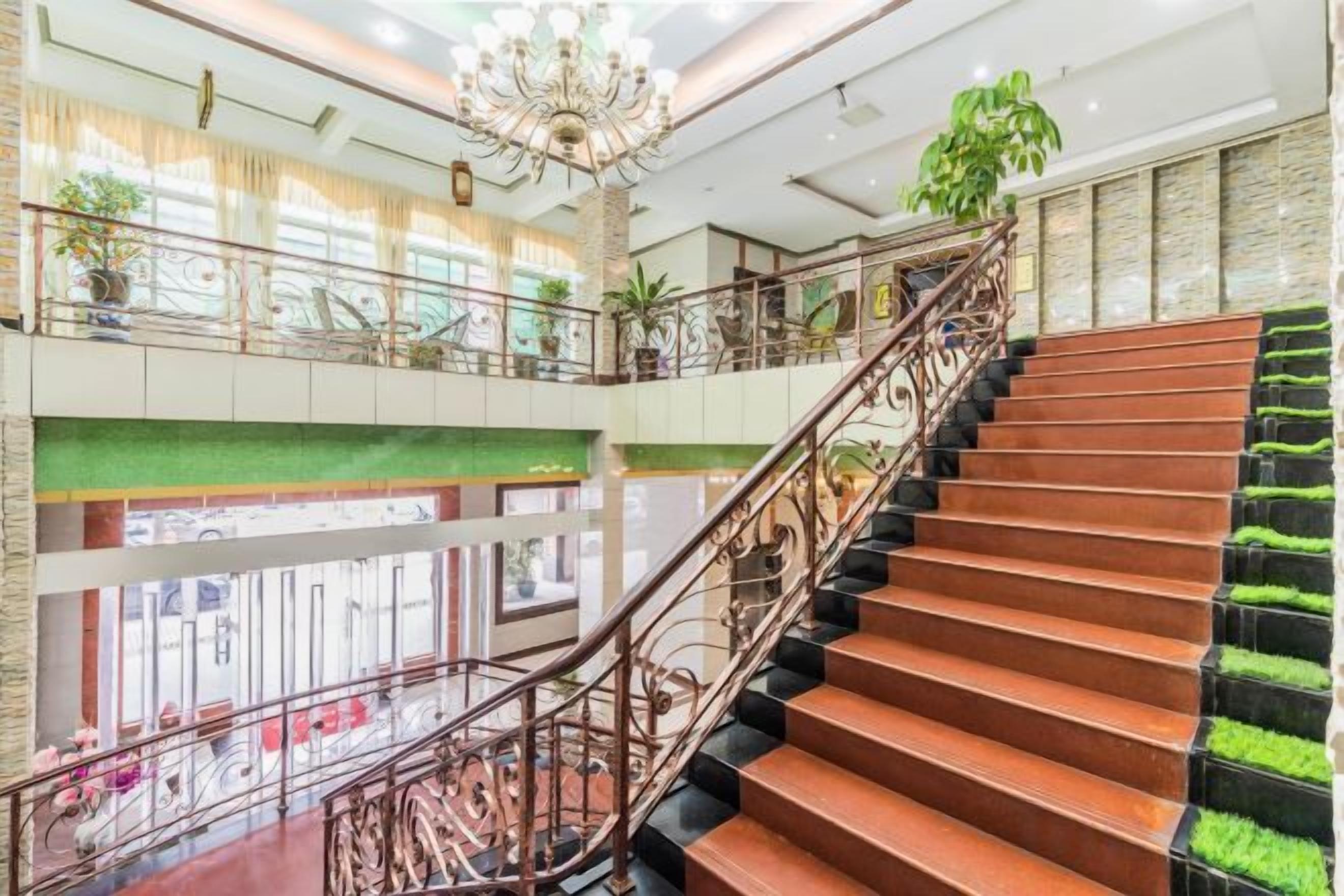 Un intérieur à plusieurs niveaux, avec un escalier, des rampes et des plantes en pot.