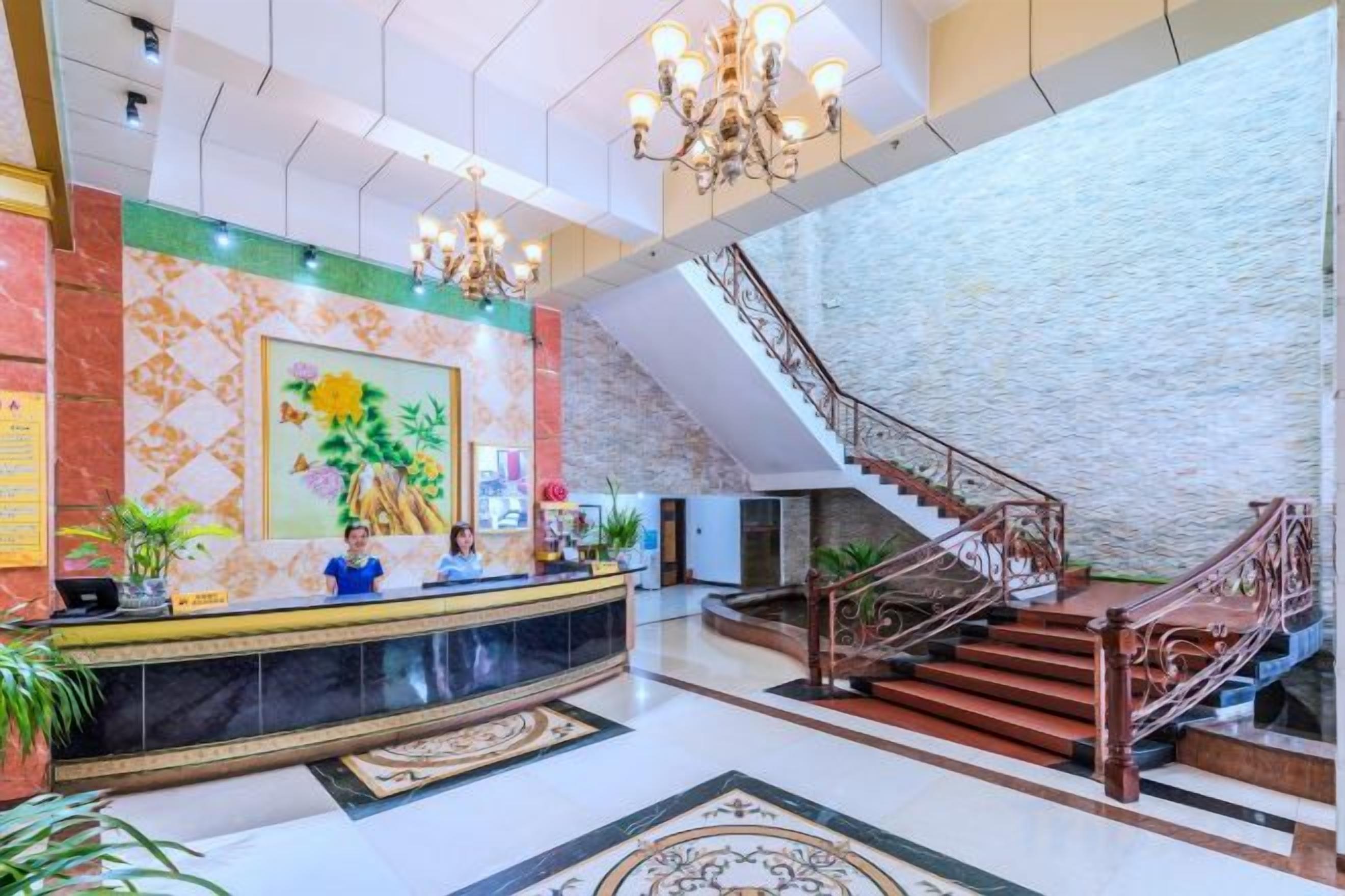 Un hall d’hôtel comprenant un comptoir d’accueil, un escalier et une grande fresque murale.
