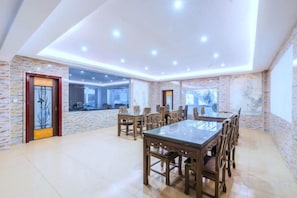 A spacious dining area with a long table and chairs, a stone wall, and a large window. - Shengli Spa Holiday Hotel (Jiangmen)