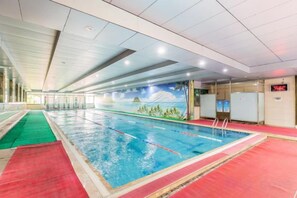 An indoor swimming pool with clear lane markings, a red carpeted area, and a mural depicting a mountainous landscape. - Shengli Spa Holiday Hotel (Jiangmen)