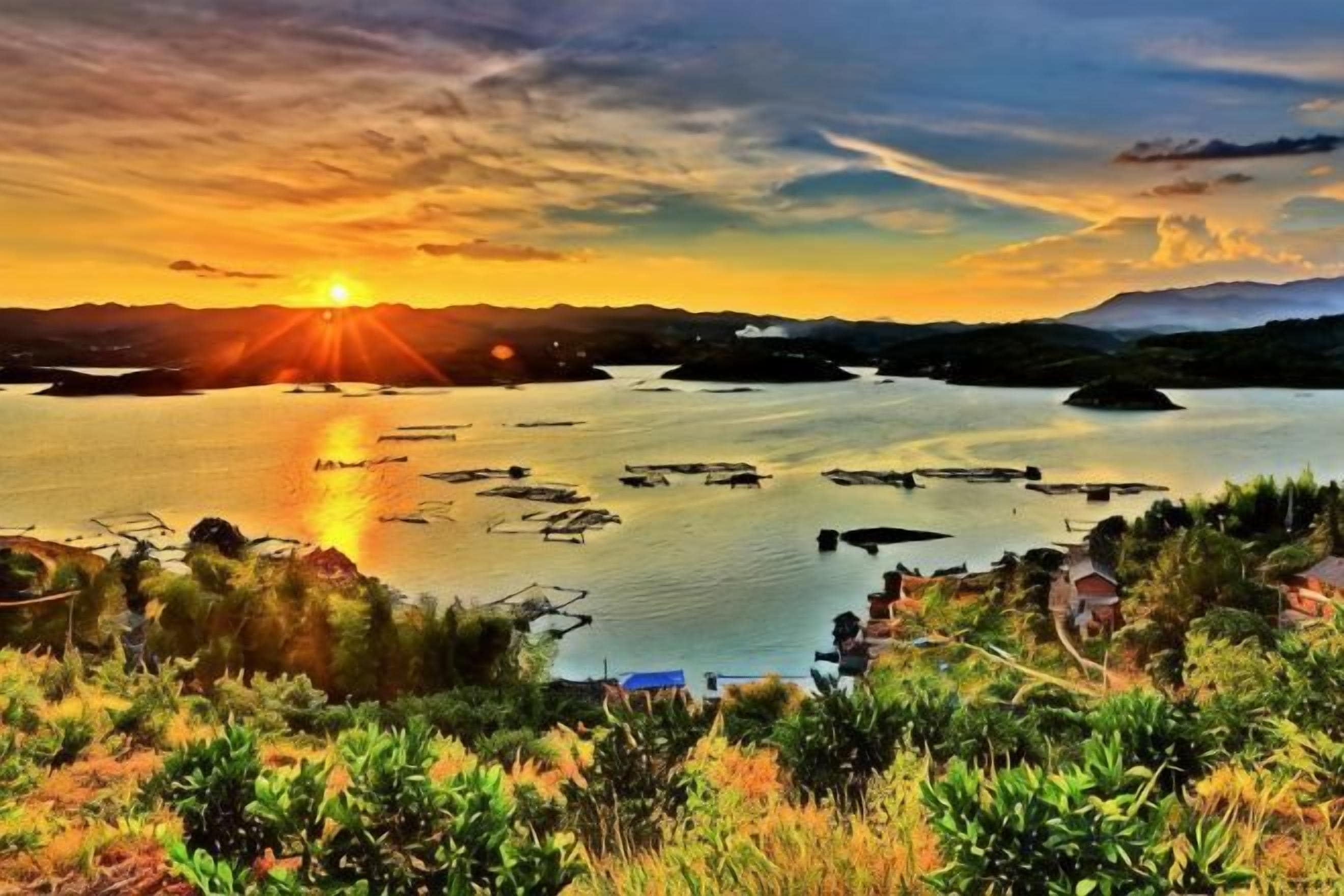 A coastal landscape with a sunset, calm water, and boats.