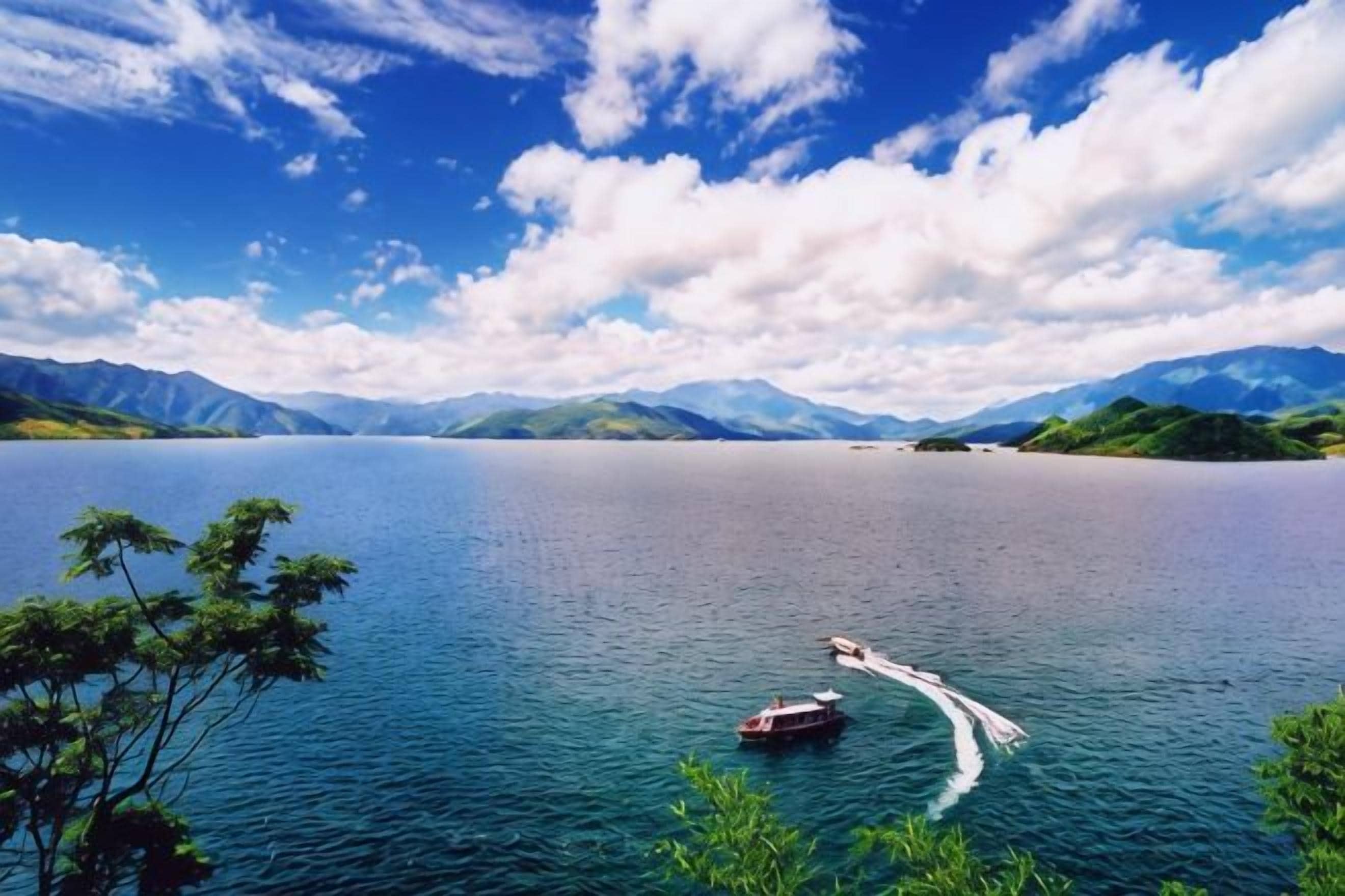A calm lake with boats, surrounded by mountains and clear skies.