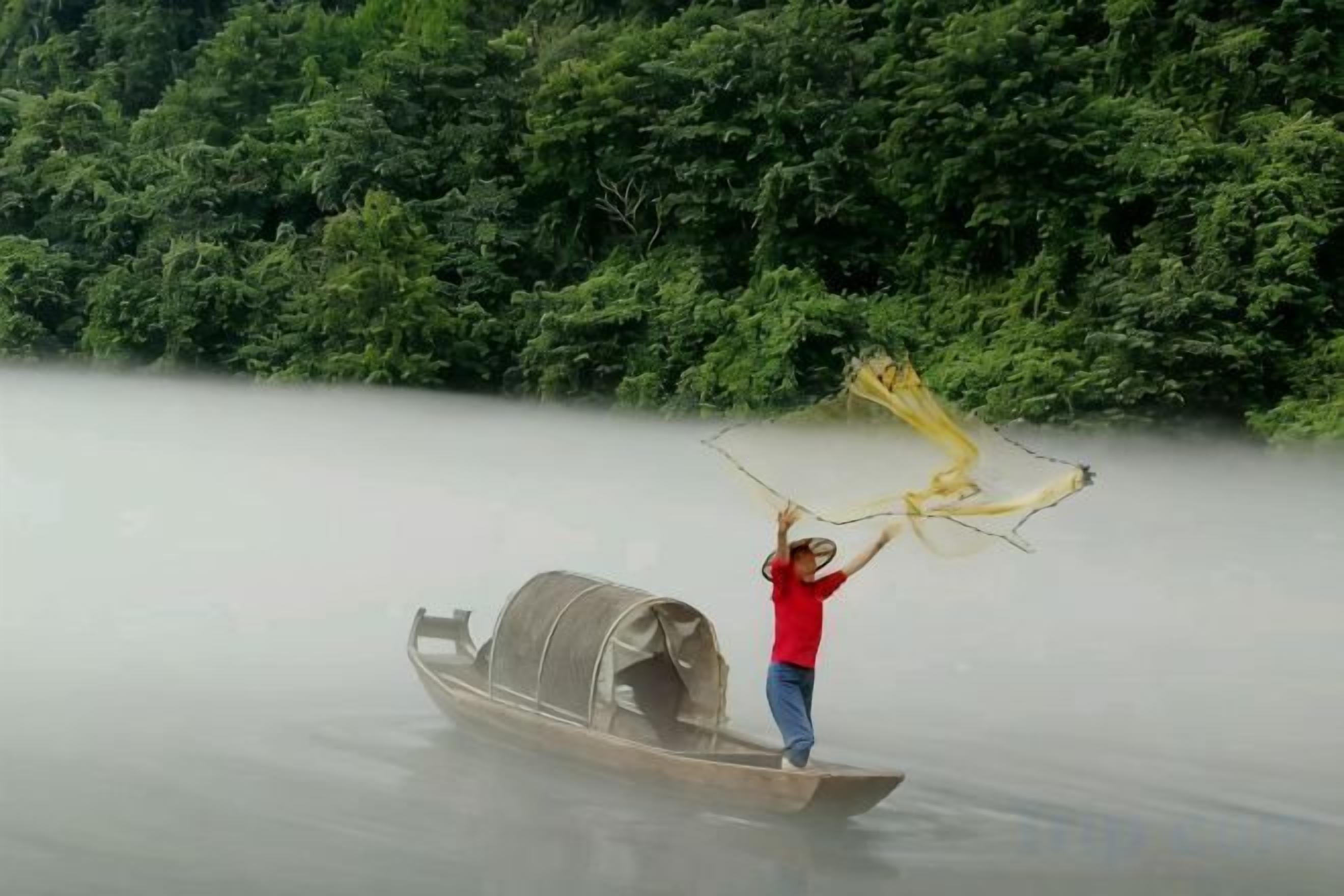 Una persona de pie en un bote en el agua, con abundante vegetación al fondo.