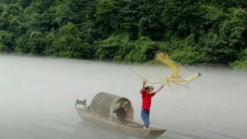 Una persona de pie en un bote en el agua, con abundante vegetación al fondo.