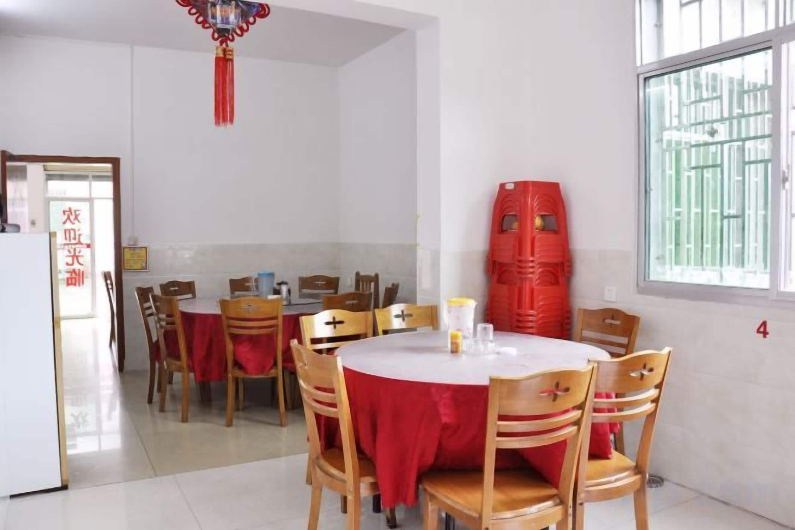 A dining area with round tables and chairs, a red tablecloth, and a window with bars.