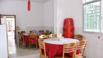 A dining area with round tables and chairs, a red tablecloth, and a window with bars.