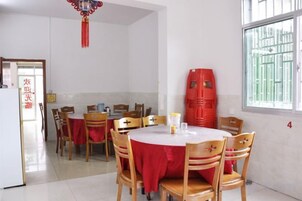 Un comedor con mesas y sillas redondas, un mantel rojo y una ventana con barrotes.