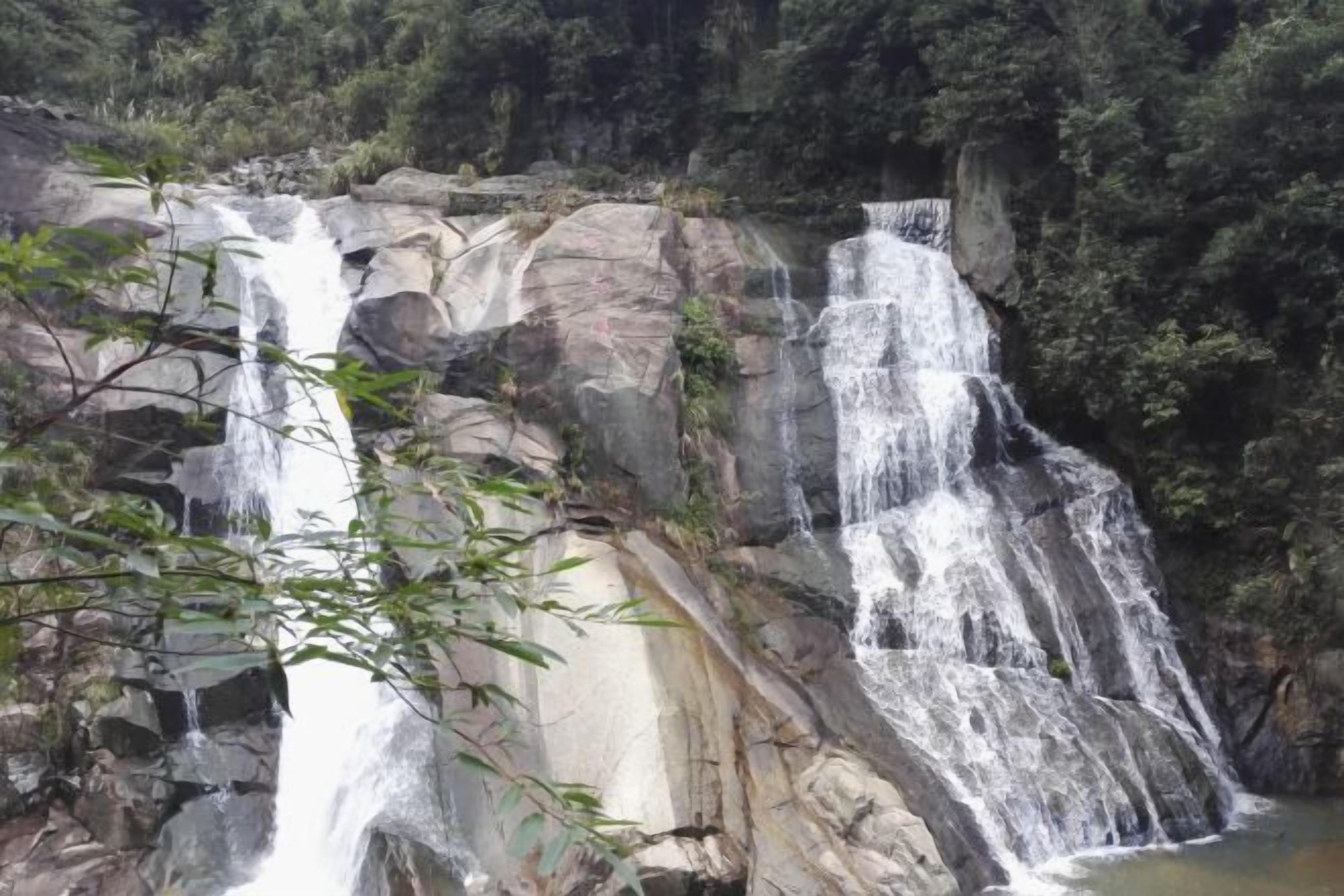 Una cascada se precipita sobre un risco rodeado de vegetación exuberante.