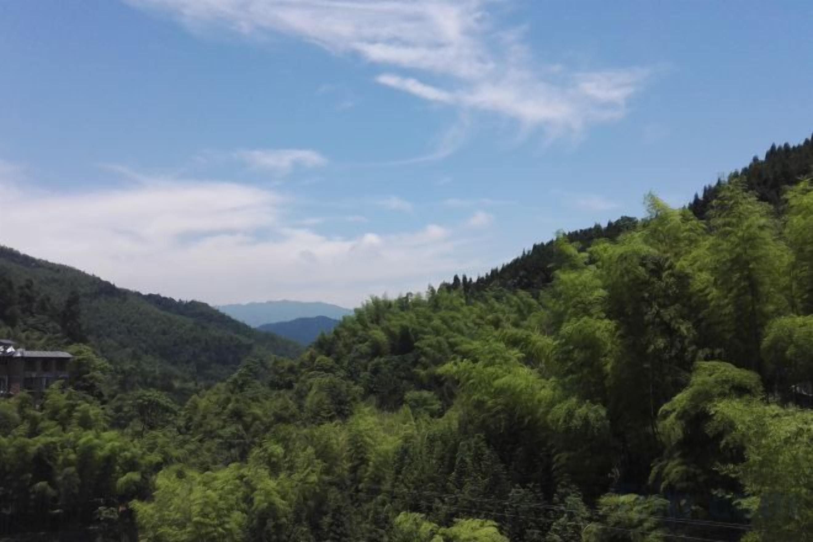 A mountainous landscape with dense greenery and a clear sky.