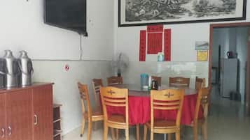 A dining area with a table, chairs, a television, and a refrigerator.