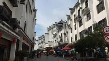 Una calle bordeada de edificios tradicionales, algunos con balcones y letreros, bajo un cielo despejado.