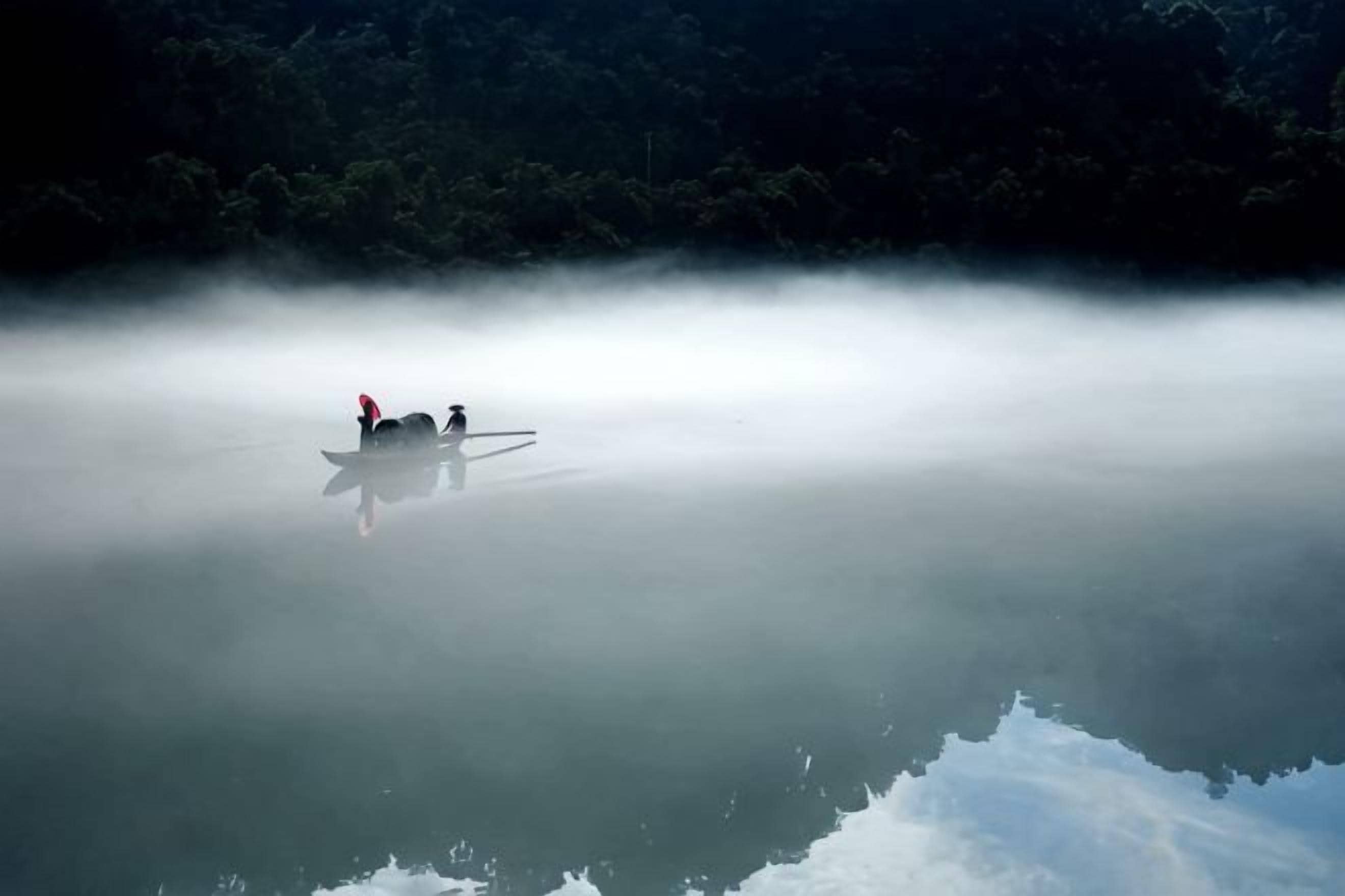 A boat on calm water with a forest in the background.