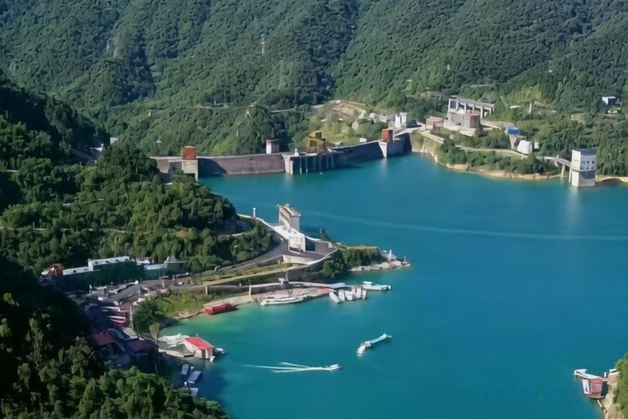 Une zone côtière comprenant un barrage, un port de plaisance et des bâtiments.