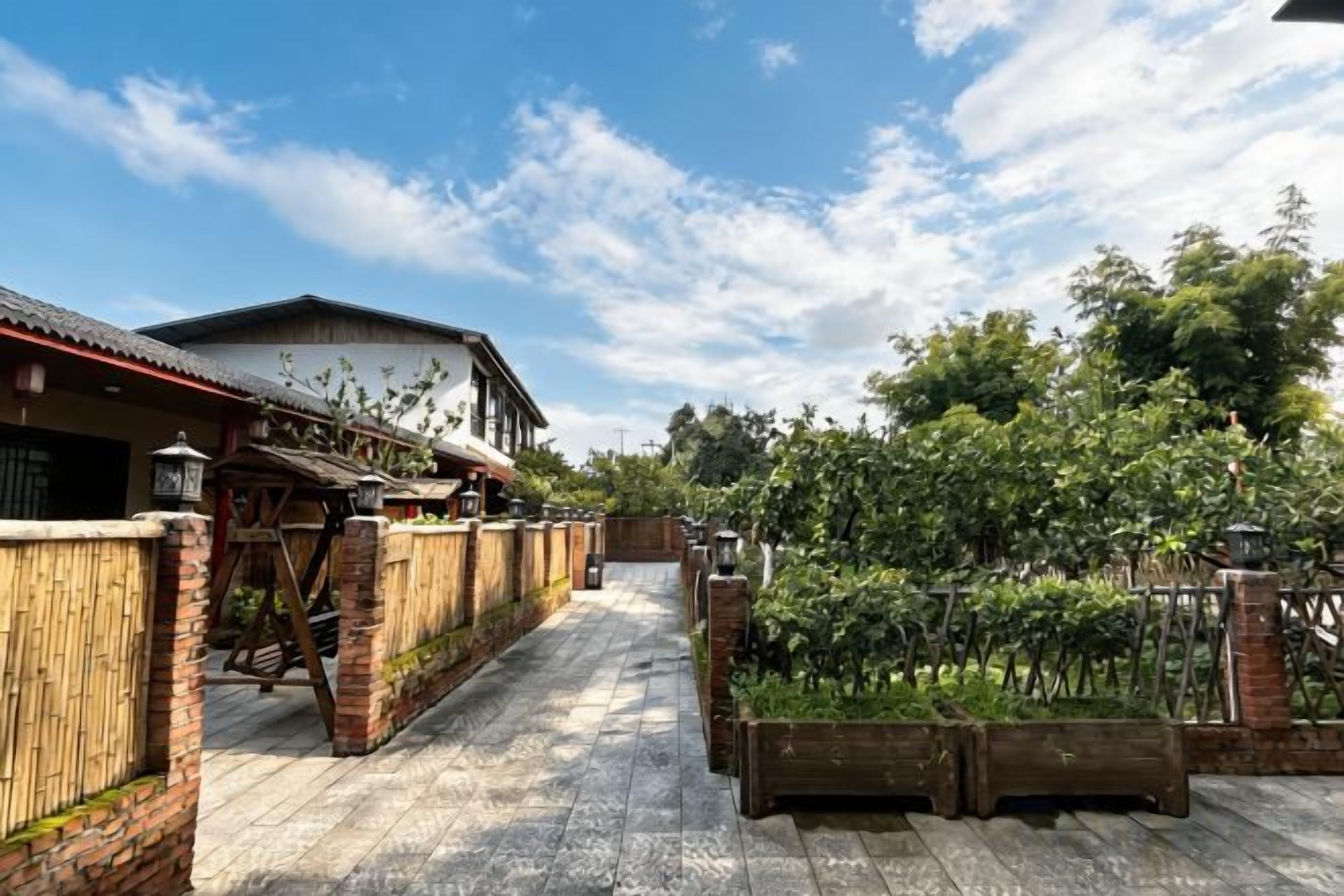 A courtyard with a wooden fence, a brick wall, and a building with a tiled roof.