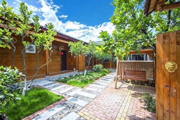 Un patio con edificios de madera, un sendero pavimentado y una puerta de madera.
