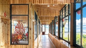 A wooden interior corridor with large windows, a Christmas tree, and a seating area. - Zhangjiajie Tianmen Mountain Villa (Tianmen Mountain Scenic Area, Lotus Airport Store) (Zhangjiajie)