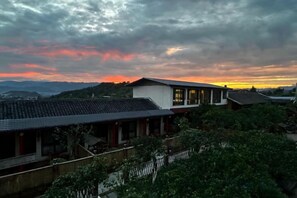 Un bâtiment traditionnel doté d’un toit en pente, entouré de verdure et offrant une vue sur le ciel.