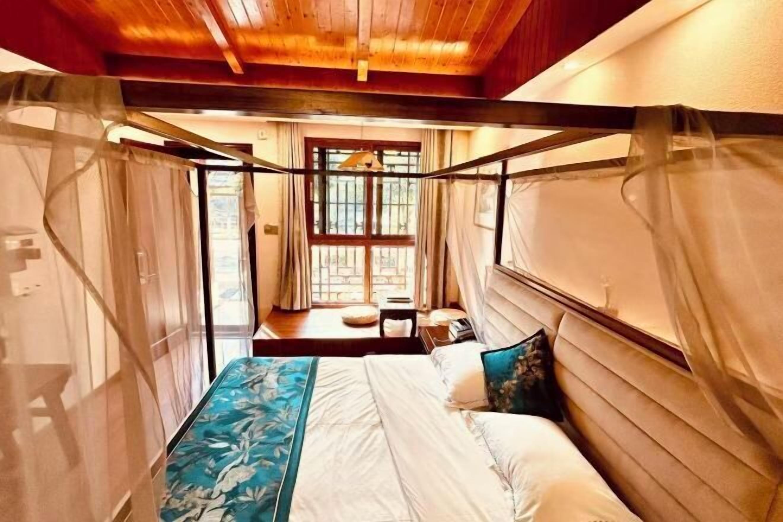 A bedroom with a bed, a window, and a view of the outdoors.