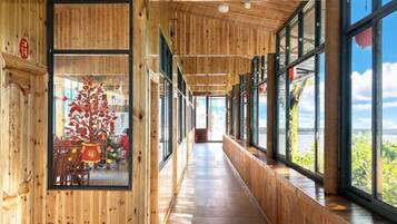 Un pasillo con paredes de madera y ventanas amplias que conduce a una habitación con un árbol de Navidad.