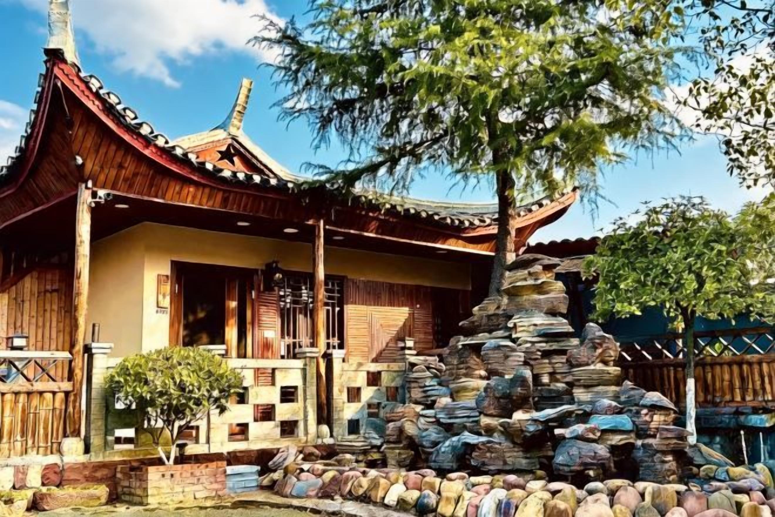 Un edificio tradicional con techo de tejas y estructura de madera, rodeado de un jardín de piedra con una formación rocosa central.