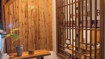 Un interior de madera con una mesa de madera, una planta en maceta y un biombo de madera tradicional.