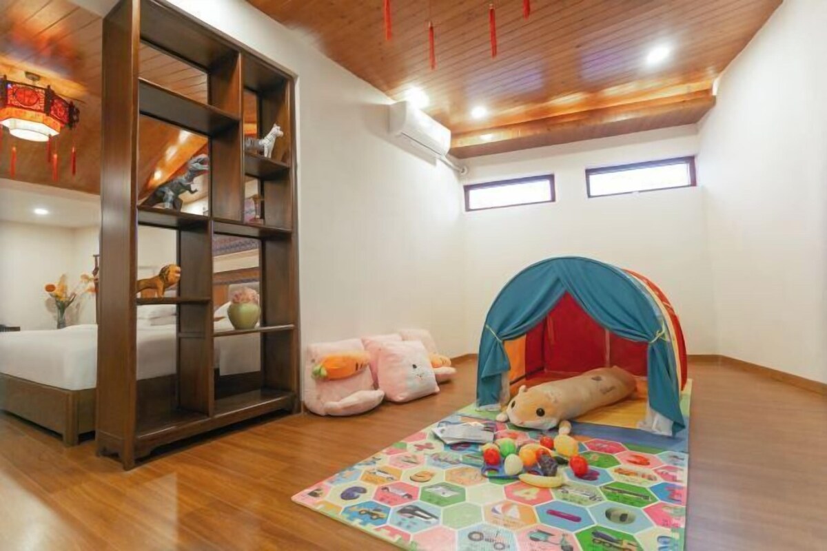 Ein Spielbereich für Kinder mit Zelt, Stofftieren und einer bunten Spieledecke.
