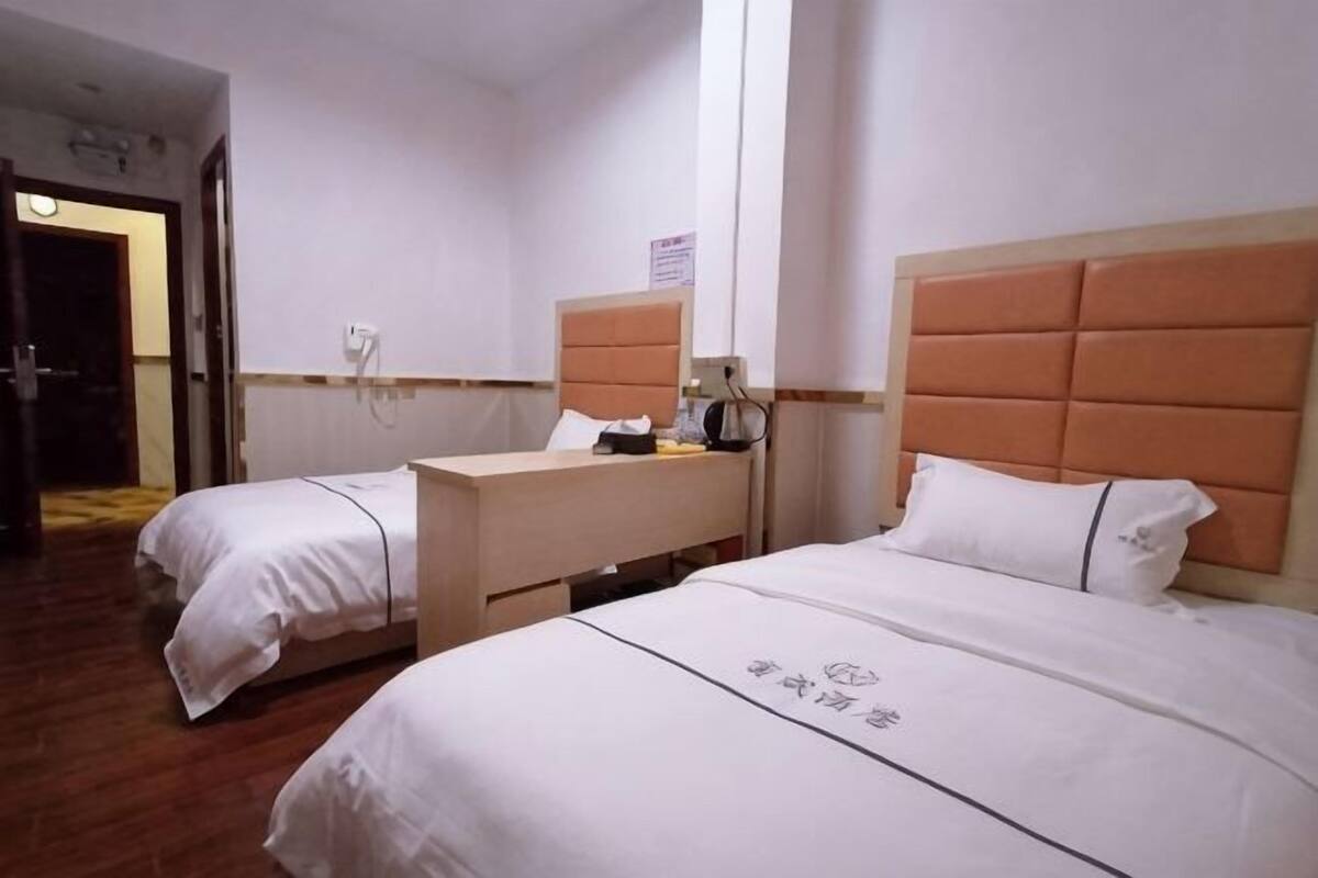 A hotel room with two beds, a wooden desk, a telephone, and a mirror on the wall.