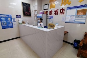 A reception desk with a digital display, a framed clock, and informational posters on the wall.