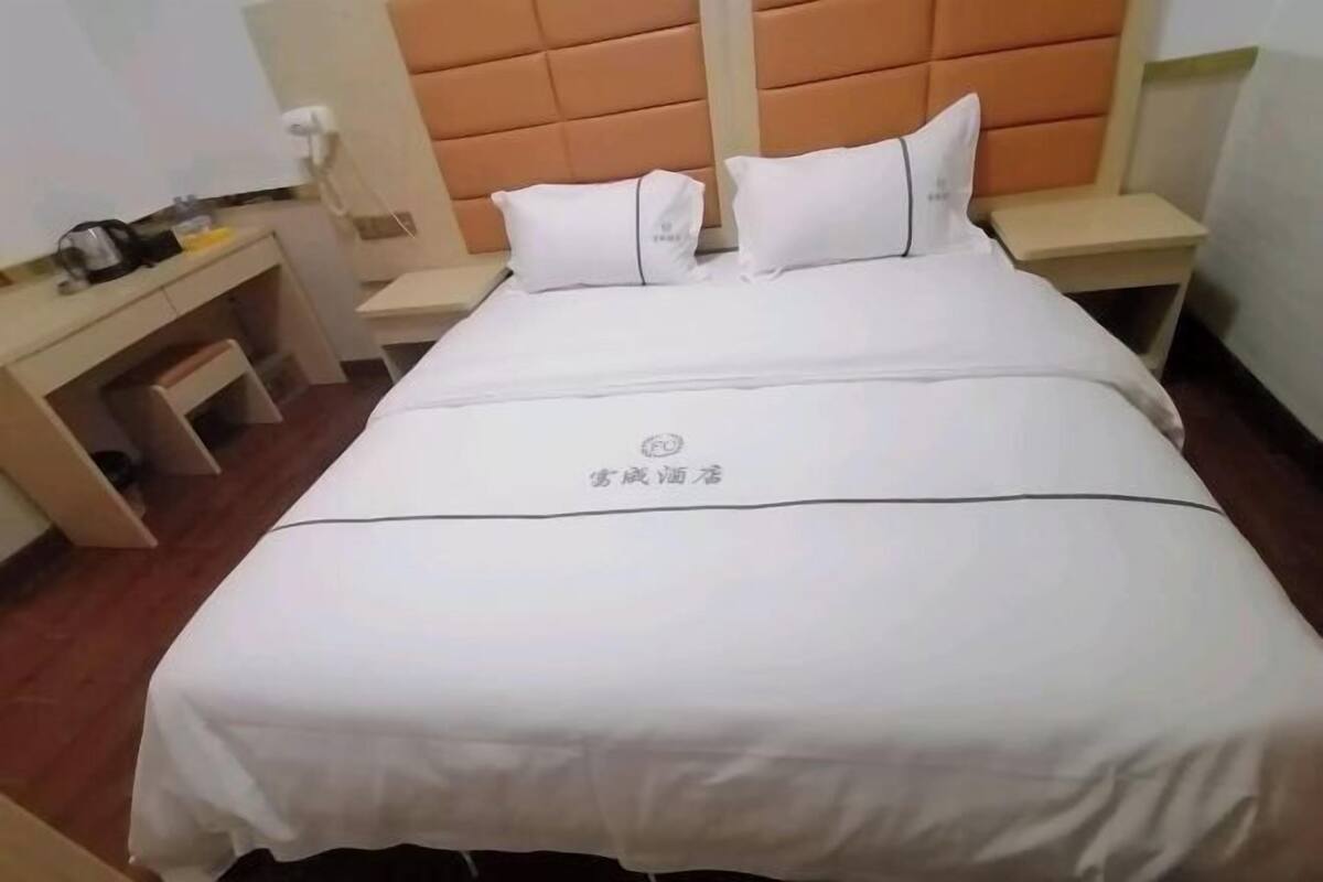 A hotel room with a bed, a desk, a chair, a nightstand, and a telephone.