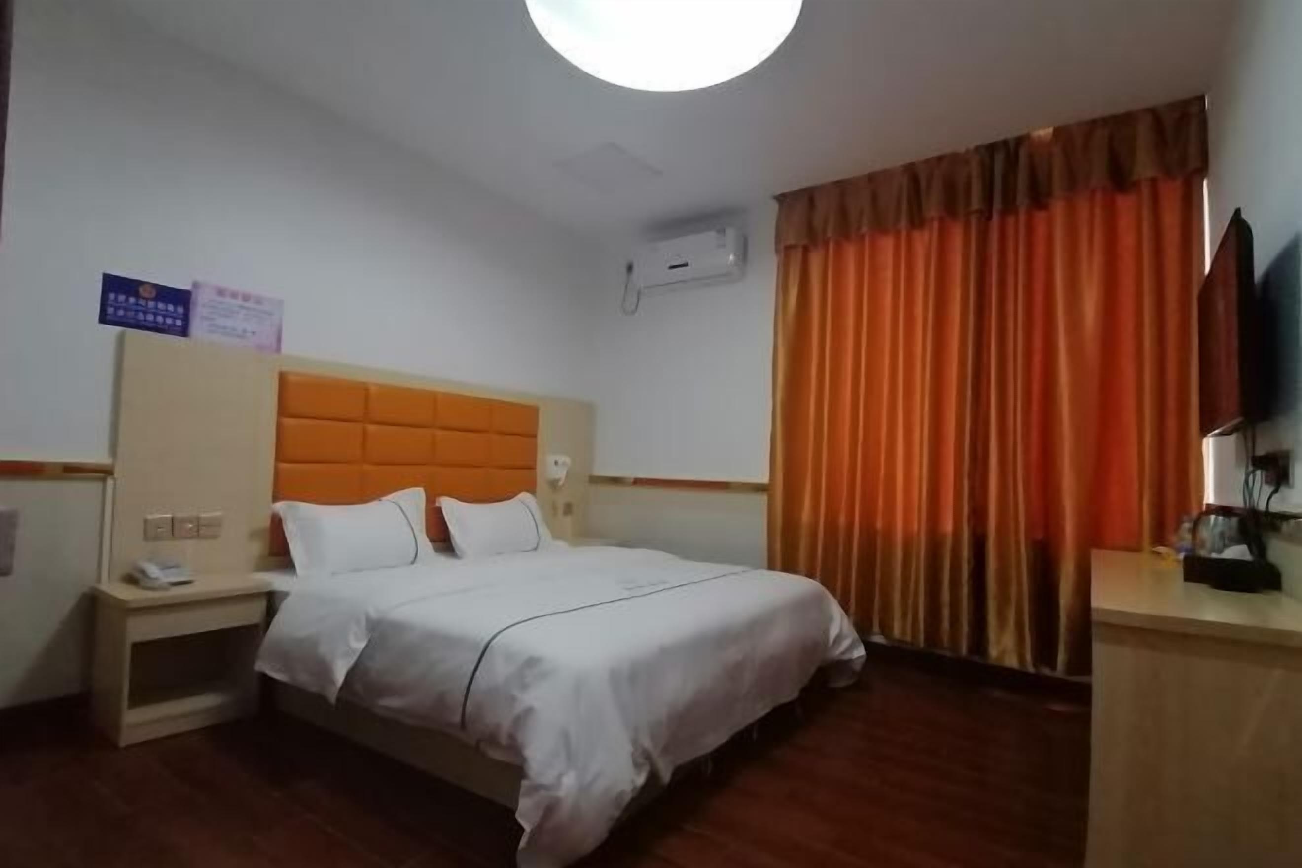 A hotel room with a bed, a nightstand, a desk, and a TV.